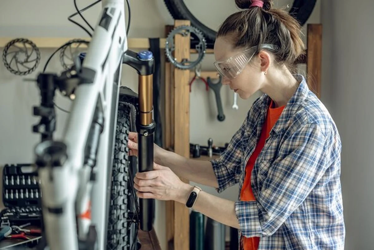 Kobieta naprawiająca rower górski w warsztacie rowerowym