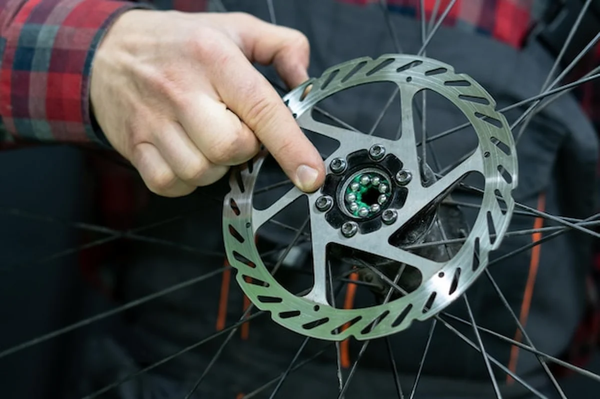 Mechanik trzyma koło w dłoni podczas wymiany smaru i łożysk piasty rowerowej