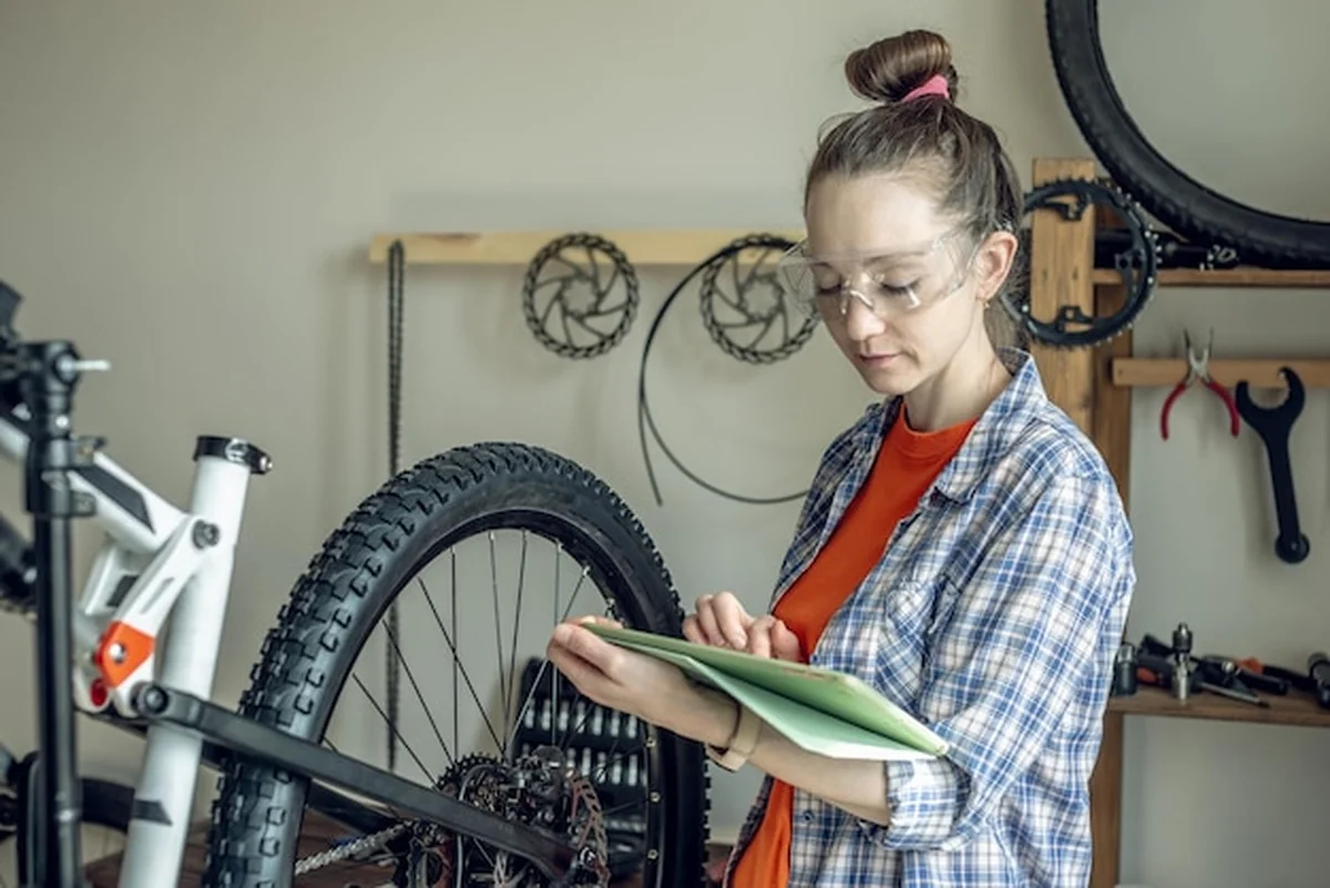 Kobieta naprawiająca rower górski w warsztacie rowerowym
