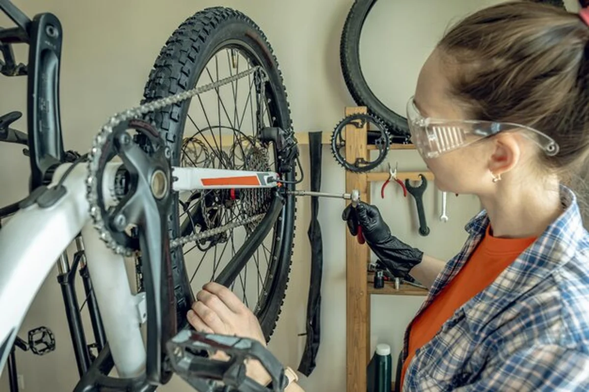 Kobieta naprawiająca rower górski w warsztacie naprawczym