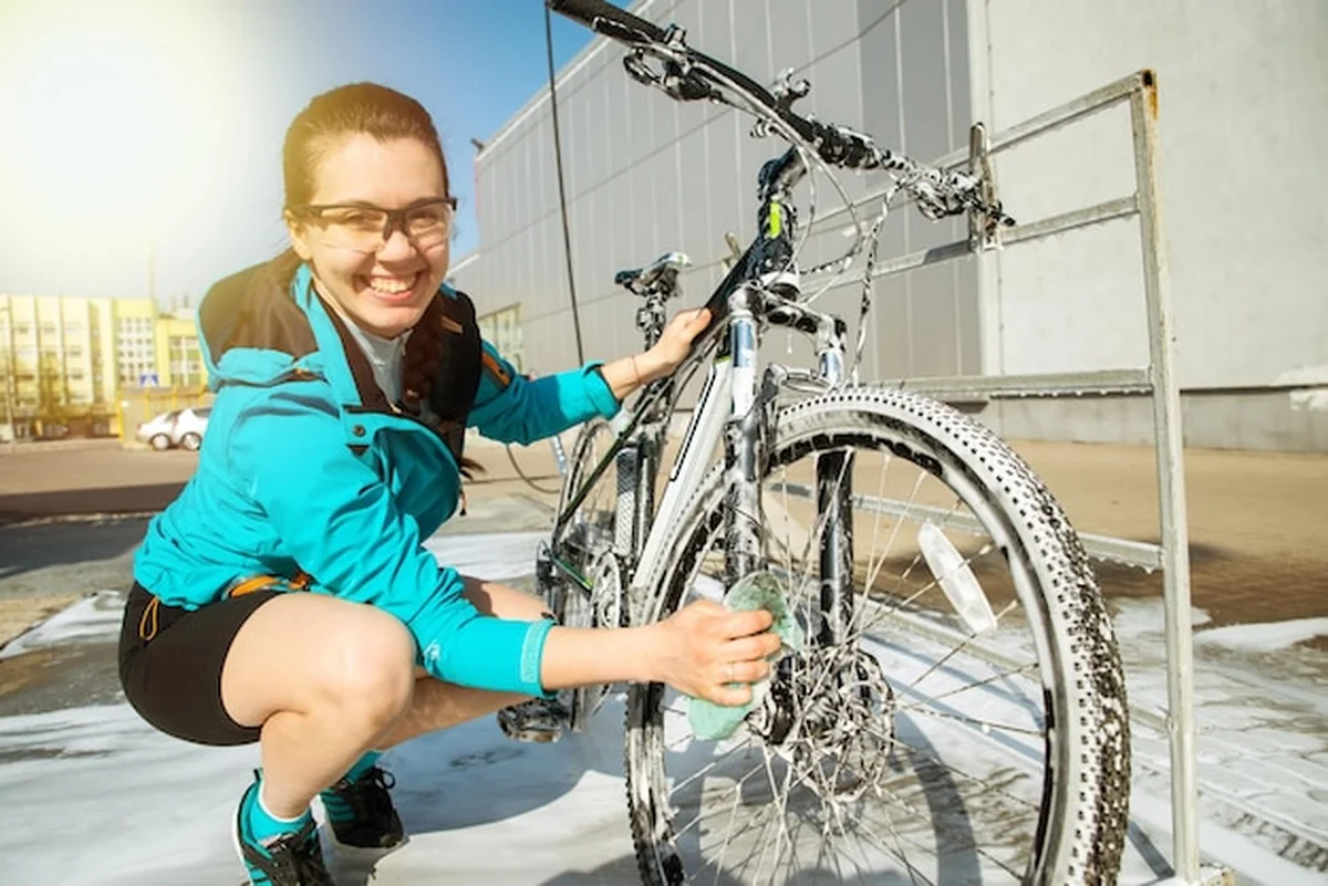 Młoda sportowa kobieta myjąca rower w samoobsługowej myjni samochodowej