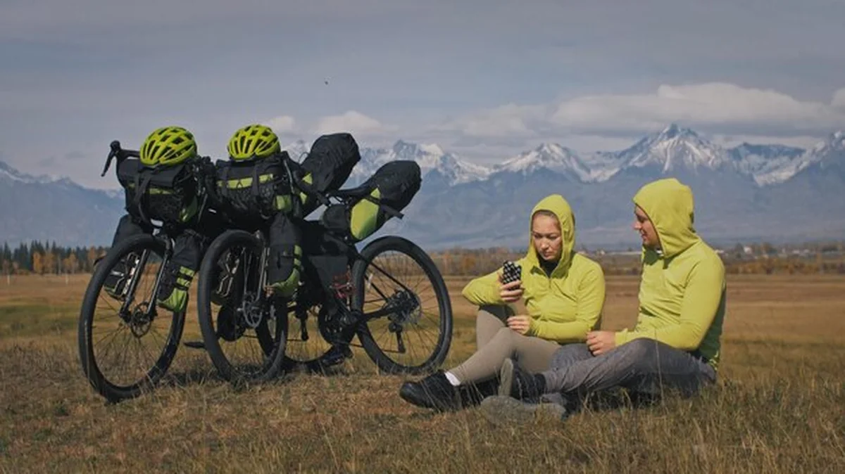 Mężczyzna i kobieta na rowerach w terenie górskim z torbami, śnieg w tle